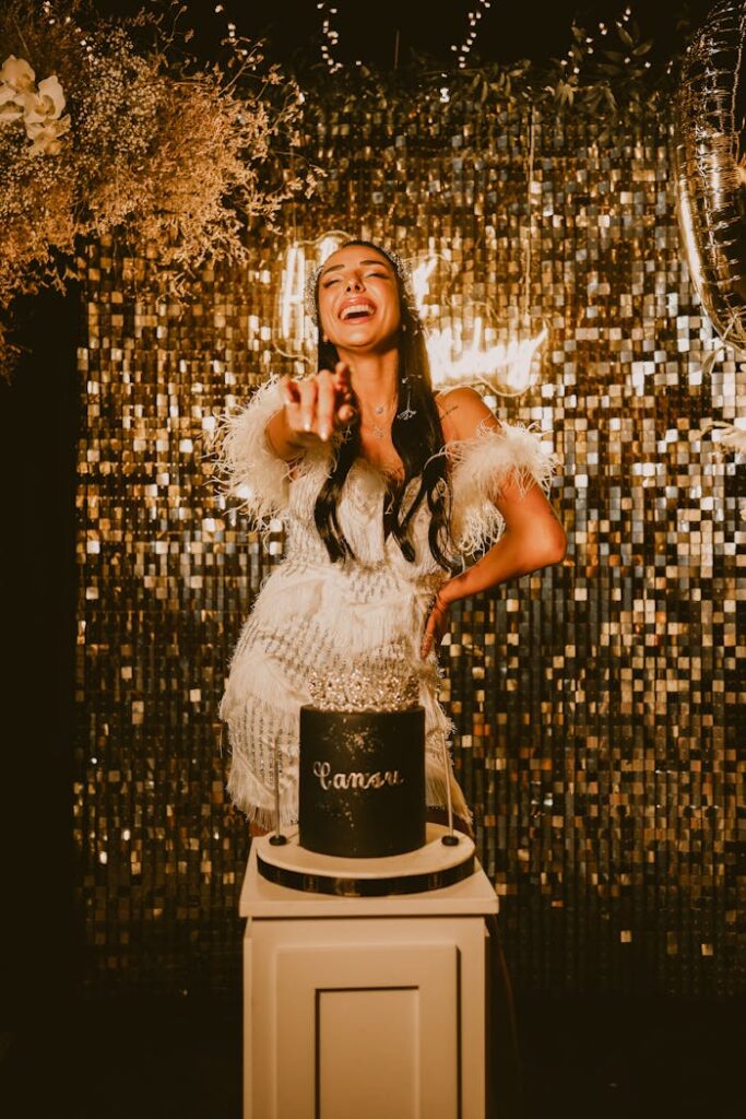 A joyful woman celebrating her birthday with a sequin backdrop and elegant cake.